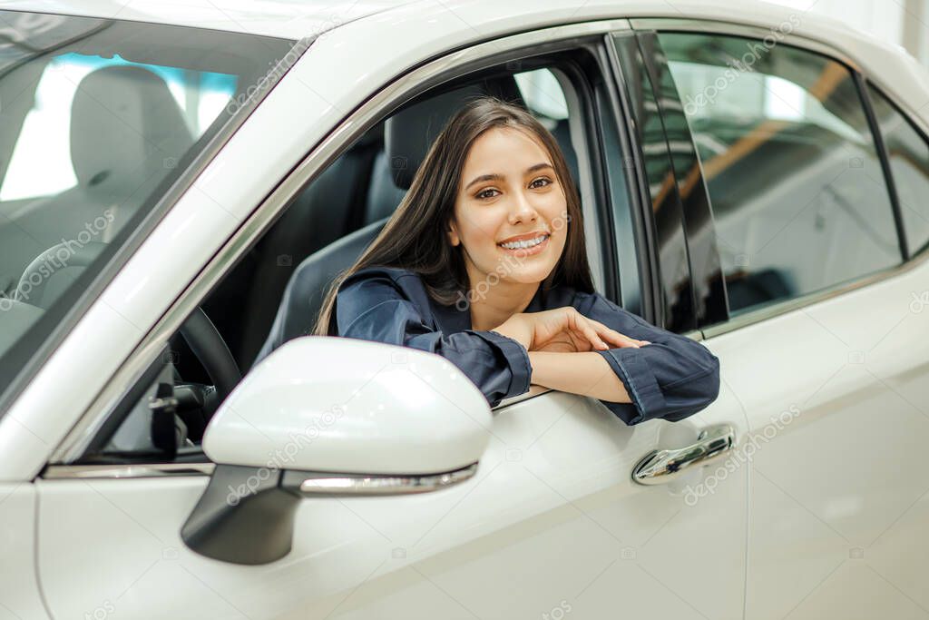 portrait of young smiling lady sitting in new car