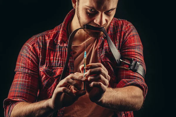 Mladý muž s drogovou posedlostí drží injekční stříkačku v ruce naplněnou injekčním lékem — Stock fotografie