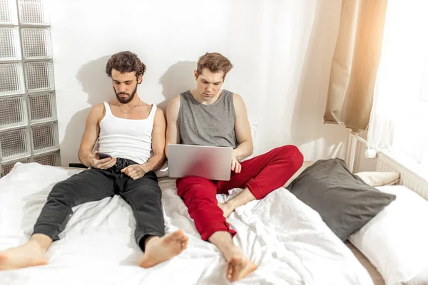 Biały geje siedzieć na łóżko za pomocą laptop — Zdjęcie stockowe
