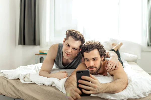 Cute homosexual couple taking selfie on bed — Stok fotoğraf