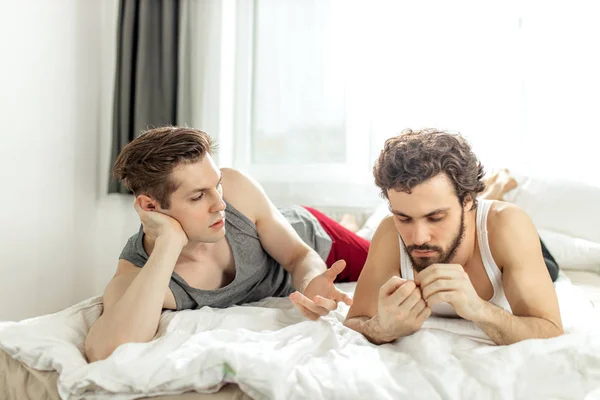 Gay couple talking on bed at home — Stockfoto