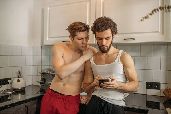 Dwóch gejów patrzeć na smartfona, w kuchni — Zdjęcie stockowe