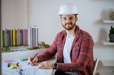 portrait of smiling engineer in white helmet in office