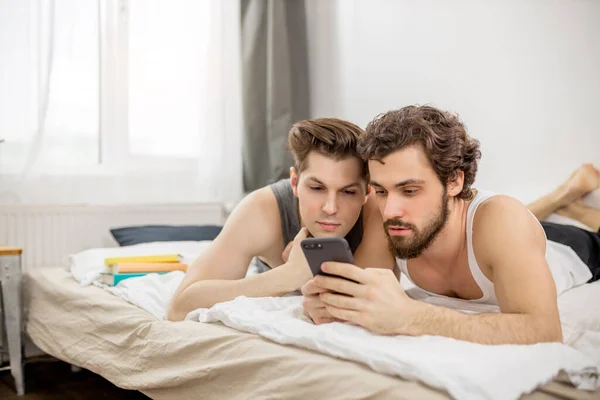 Attractive gays in love, lie on bed at home — Stok fotoğraf