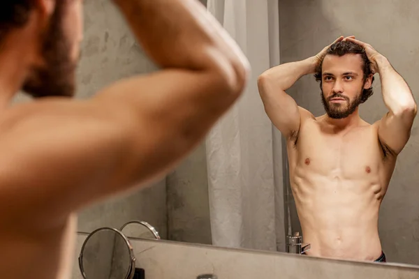 man examining his face in mirror