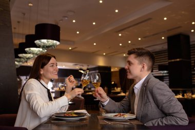 Kafkasyalı çift restoranda bardak tokuşturuyor.