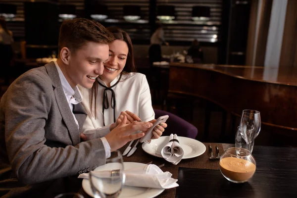 happy caucasian couple use smartphone in restaurant