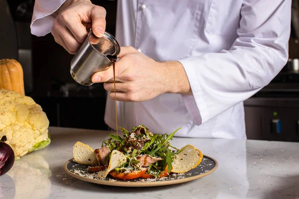Cozinheiro-chef despeje suavemente o molho na salada — Fotografia de Stock