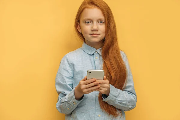 Zoet rood harig kind meisje met smartphone — Stockfoto
