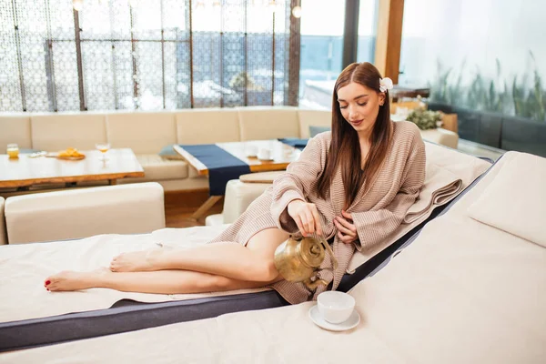 Atractiva dama vertiendo té saludable fragante de la tetera en el spa — Foto de Stock