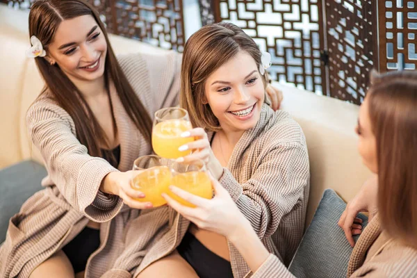 Señoras felices tintineo vasos de jugo en el spa — Foto de Stock