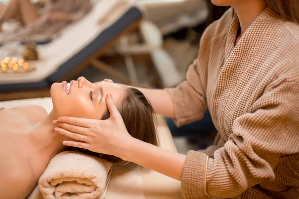 Mujer joven recibiendo masaje en la cabeza en el salón de spa —  Fotos de Stock