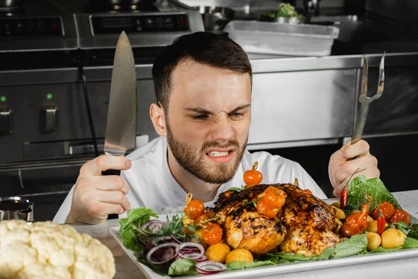 Grappige kok met gekookt vlees in de keuken — Stockfoto
