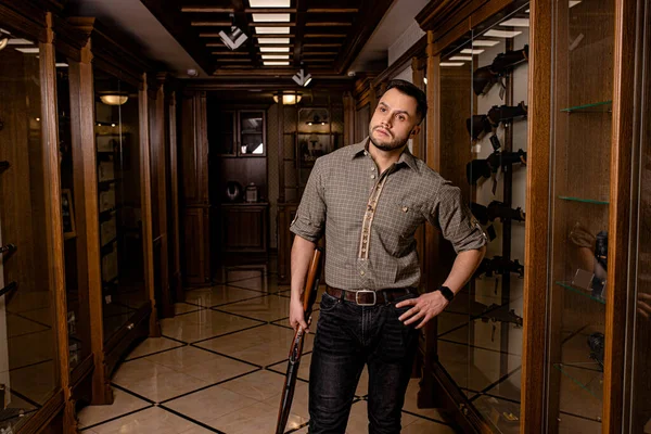Mladý dospělý muž s puškou v obchodě se zbraněmi — Stock fotografie