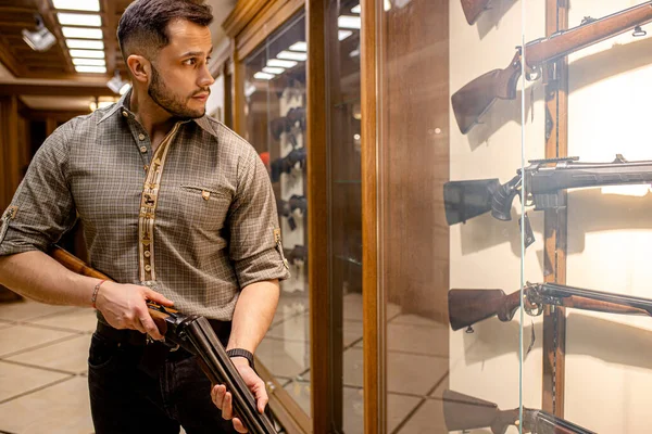 Bonito caucasiano cara procurando bom arma rifle — Fotografia de Stock