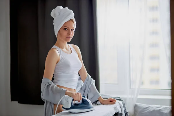 Young beautiful woman ironing clothes at home — Stock Photo, Image