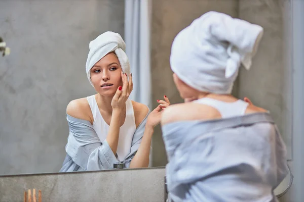 Hermosa mujer caucásica mirar a la reflexión en el espejo en el baño — Foto de Stock