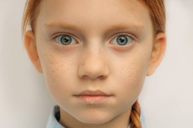 Büyük mavi gözlü ve kızıl saçlı bir çocuğun yakın plan portresi.