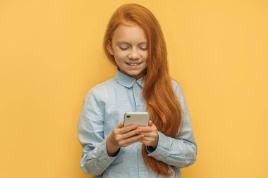 Akıllı telefonlu güzel kızıl saçlı bir kızın portresi.