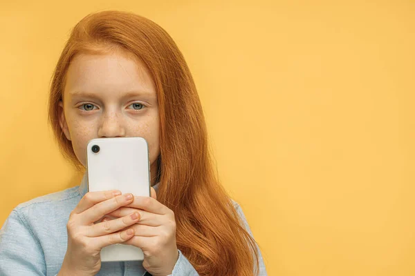 Крупным планом портрет маленькой белой девушки со смартфоном — стоковое фото