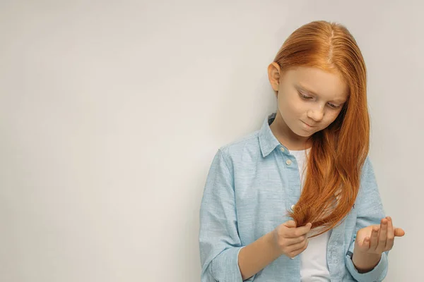 Bambino dai capelli rossi guarda le doppie punte sui capelli — Foto Stock