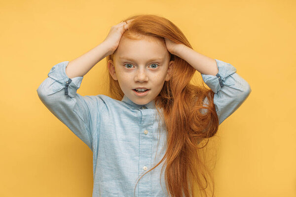 portrait of surprised red haired girl isolated over yellow background