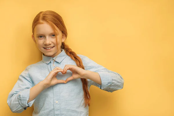 Linda menina caucasiana mostrar coração feito de mãos — Fotografia de Stock