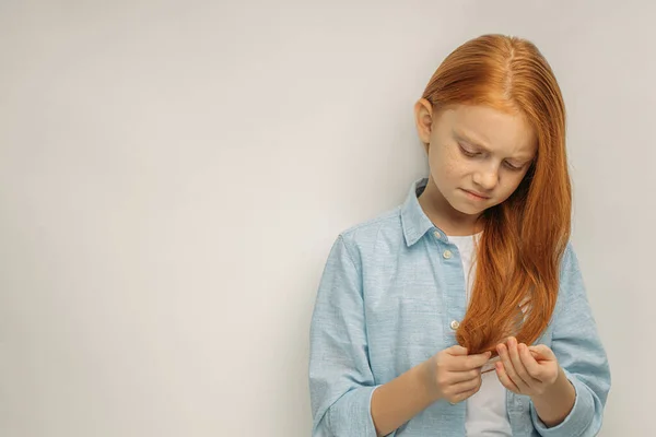 Menina descontente olha para pontas duplas no cabelo — Fotografia de Stock
