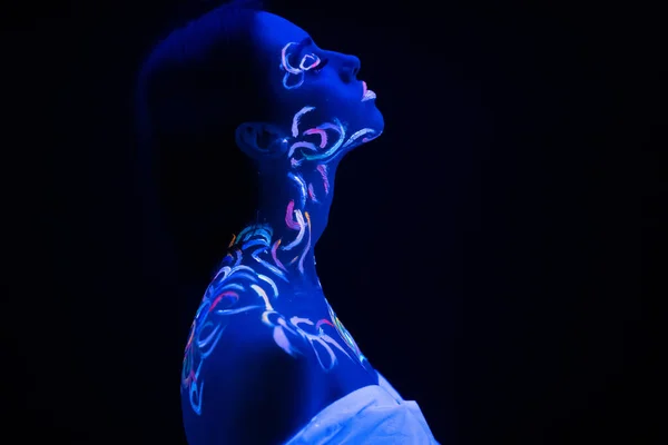 Sidovy på vacker ung kvinna med fluorescerande tryck på huden — Stockfoto