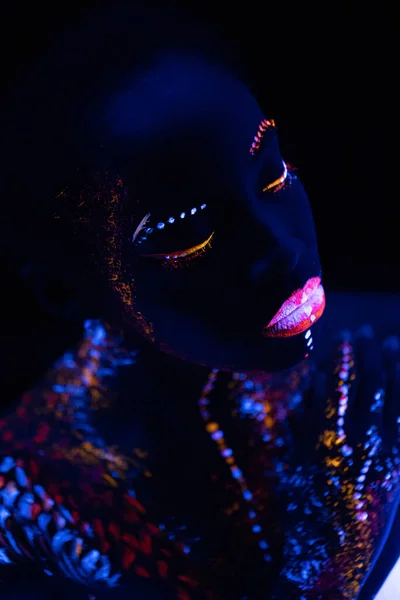 fluorescent makeup on womans skin glowing under ultraviolet light