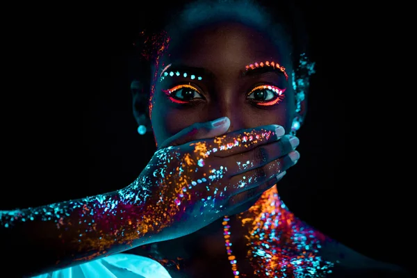 Mujer africana con impresiones fluorescentes en la cara y la boca cerrada —  Fotos de Stock