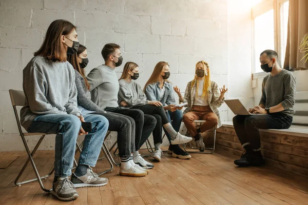 Jóvenes se sientan juntos en máscaras — Foto de Stock