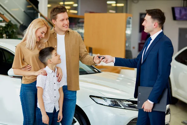 Consultor confiante bonito dar chaves de carro para novos proprietários — Fotografia de Stock