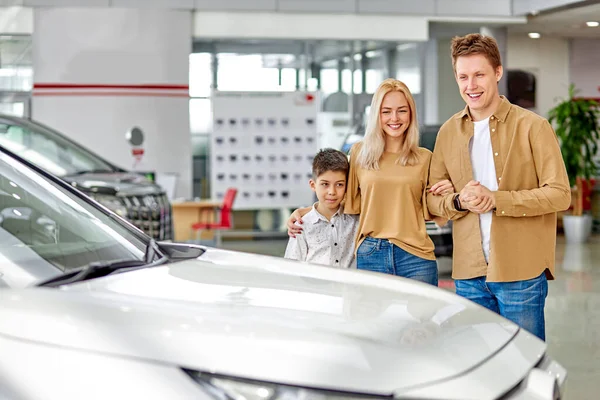 Família caucasiana feliz agora os proprietários de novo belo carro — Fotografia de Stock