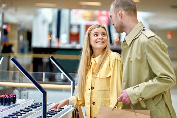 woman show on something in store, ask husband to buy it