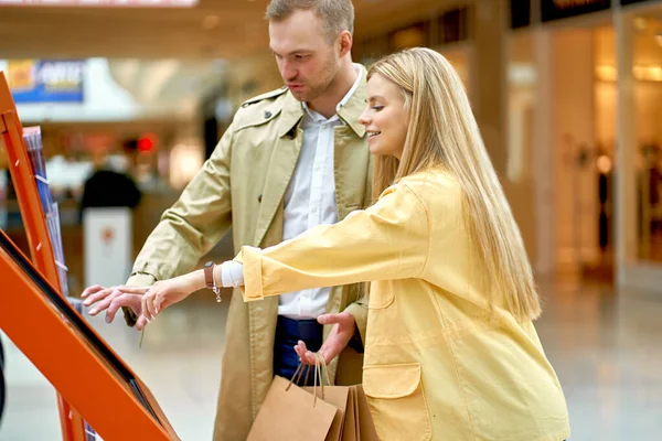 Casal procurando loja específica no shopping — Fotografia de Stock