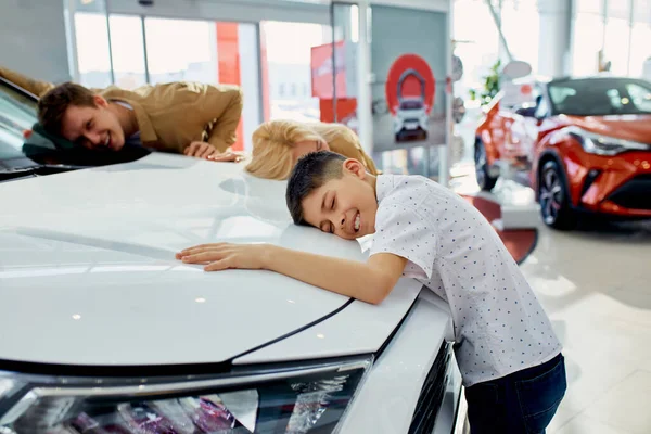 Rolig far och barn pojke kramar ny bil i återförsäljaravtal — Stockfoto