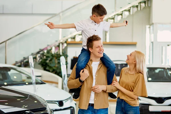 Jovem família com criança feliz depois de obter as chaves de seu novo carro — Fotografia de Stock