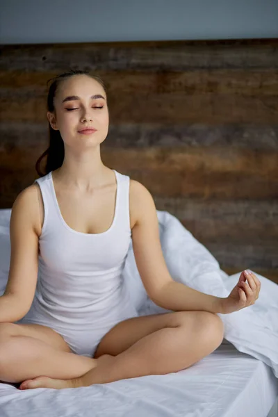 Giovane e bella donna meditando sul letto — Foto Stock