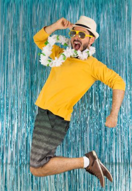 Yeşil ve sarı elbiseli sakallı adam, güneş gözlüğü ve Hawaii kolyesi. Brezilya karnavalı, yıl sonu arifesi, coşku ve eğlence. Renkli ve parlak arkaplan.