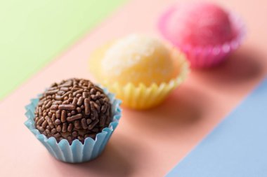 Brezilya tatlıları: Brigadeiro, Beijinho ve Bicho de Pe. Şekerler düz çizgide. Renkli arkaplan.