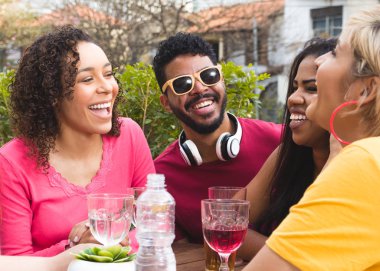 Genç yetişkinler dışarıda takılıyor, restoranda eğleniyor. Çok kültürlü öğrenciler kafenin dışındaki barda parti yapıyorlar. Bahar, ılık, birliktelik, yaşam tarzı, çeşitlilik kavramı.