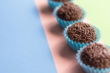 Brigadeiro Brezilya 'dan tipik ev yapımı çikolatalı trüf. Kakao, konsantre süt ve çikolata parçacıkları. Çocukların doğum günü partisinde yaygındır. Şeker topları düz çizgide. Renkli arkaplan.