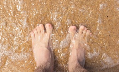 Kumsalda gezgin ayakları. Kristal berrak su.