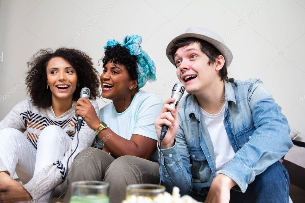 Multiethnic university people singing together karaoke in living room. Cheerful, happy youth moment