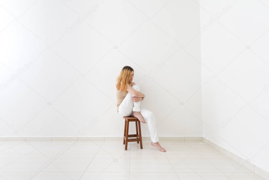 Sad barefoot woman sitting on chair. Concept of depression, loneliness, sadness and sorrow.