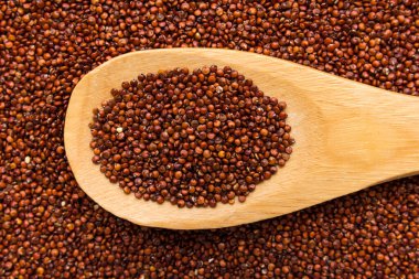 Chenopodium kinoa, Kırmızı kinoa tohumunun bilimsel adıdır. Tahta kaşıkta tahıllar. Kapat..