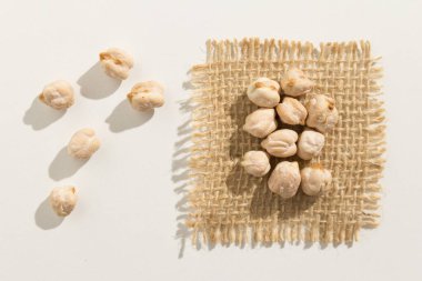 Cicer arietinum, nohut baklasının bilimsel adıdır. Ayrıca Garbanzo fasulyesi, Nohut veya Grao de Bico olarak da bilinir. Beyaz masaya yayılmış tahılları kapat.