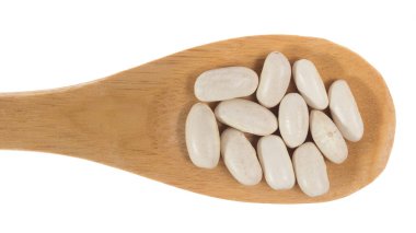 Phaseolus vulgaris, Donanma Fasulye Baklagil 'inin bilimsel adıdır. Haricot, Pearl Bean ve Feijao Branco olarak da bilinir. Tahta bambu kaşığı üzerinde tahıllar. Beyaz arkaplan.