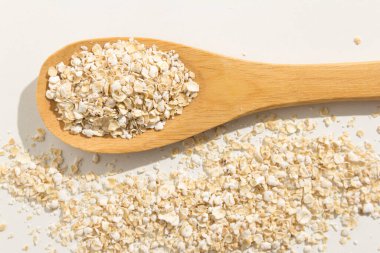 Avena Sativa, Yulaf gevreğinin bilimsel adıdır. Aveia ya da Avena olarak da bilinir. Tahta kaşıkta sağlıklı taneler. Beyaz arkaplan.